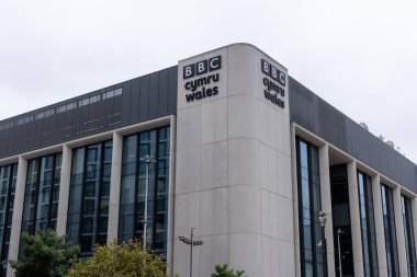 CARDIFF, İngiltere - 8 AĞUSTOS 2025 - BBC Cymru Wales 'in Cardiff, Galler' deki modern binası, büyük cam pencereler ve BBC 'nin belirgin tabelaları