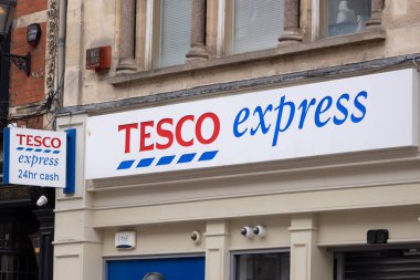 CARDIFF, İngiltere - 8 AĞUSTOS 2025 - Cardiff, Galler 'deki Tesco Express mağazası, logosunu ve 24 saat nakit servisini sergiliyor