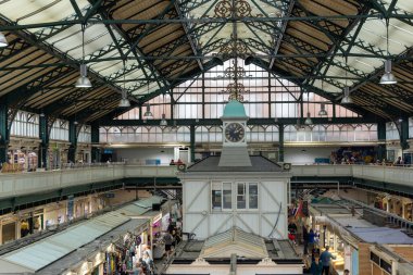 CARDIFF, İngiltere - 8 AĞUSTOS 2025 - Cardiff, Galler 'deki Cardiff Market' in iç görünümü, saat kulesi, tezgahları ve yerel ürünleri satın alan müşterileri gösteriyor