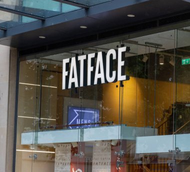 CARDIFF, İngiltere - 8 AĞUSTOS 2025 - Cardiff, Galler 'deki FatFace giyim mağazasının modern vitrininde belirgin markalar ve tabelalar sergileniyor