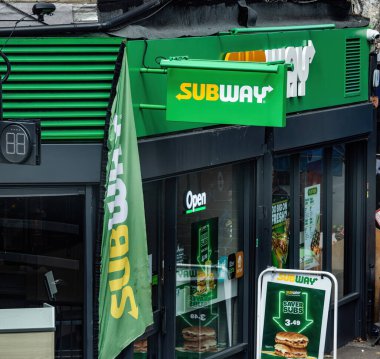 LONDON, UK - 5 AĞUSTOS 2025 - Londra 'da tanınmış markalaşma, açık işaret ve kurtarıcı denizaltılar için promosyon tabelaları ile metro restoranı cephesi