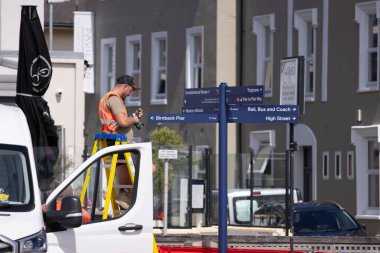 WESTON, İngiltere - 8 AĞUSTOS 2025 - Weston Super Mare 'deki bir sokak tabelasını kuran ya da tamir eden tamirci, bir merdiven ve bir minibüs kullanıyor