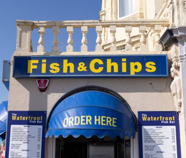 Weston Super Mare, İngiltere 'de geleneksel balık ve patates kızartması dükkanı, menüsünü ve fiyatlarını mavi bir tente altında sergiliyor.