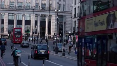 LONDON, UK - 5 AĞUSTOS 2025 - Tipik Londra sokak manzarası kırmızı çift katlı otobüsler, siyah taksiler, bisikletçiler ve yayalar Piccadilly 'deki Wolseley restoranının önünden geçiyor