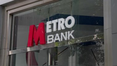 CARDIFF, İngiltere - 8 AĞUSTOS 2025 - Metro Bankası logosu Cardiff, Galler, Birleşik Krallık 'taki ağaçları yansıtan cam bir binada sergilendi