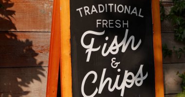 LONDON, İngiltere - 5 AĞUSTOS 2025 - Londra 'da geleneksel taze balık ve patates kızartması reklamı yapan karton pano, İngiliz mutfak kültürünü yansıtıyor