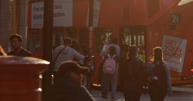 LONDON, İngiltere - 5 AĞUSTOS 2025 - Turistler gün batımında Londra 'da çift katlı bir otobüse binecek ve canlı bir şehir hayatı manzarası yaratacaklar.