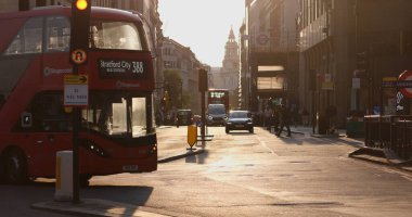 LONDON, UK - 5 AĞUSTOS 2025 - Kırmızı çift katlı otobüs Bank Station yakınlarında gün batımında Londra 'dan geçiyor, arka planda St. Paul Katedrali var