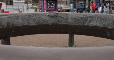 CARDIFF, İngiltere - 8 AĞUSTOS 2025 - Cardiff Körfezi yaylım ateşi ve çevresini gösteren dairesel bronz heykele yakın çekim