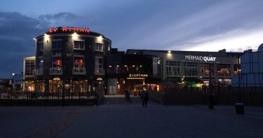 CARDIFF, İngiltere - 8 AĞUSTOS 2025 - Alacakaranlıkta Cardiff Körfezi Aydınlatılmış Everyman Sineması ve Denizkızı Quay eğlence kompleksi