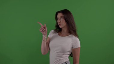 Yeşil ekran arka planında parmağı olan genç bir kadın.