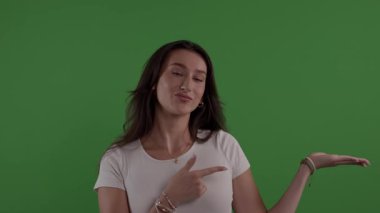 Yeşil ekranda elini gösteren genç bir kadın.