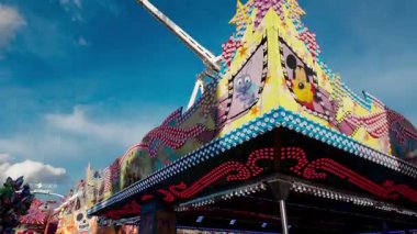 LUXEMBURG, EUROPE - 1 Eylül 2025 - Lüksemburg 'daki Schuberfouer lunaparkında mavi gökyüzünün altında parlayan çizgi film karakterleriyle dolu Atlıkarınca