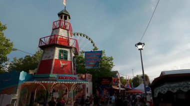LUXEMBURG, EUROPE - 1 Eylül 2025 - Lüksemburg 'un en büyük lunaparkı olan Schueberfouer' de eğlenen turistler, deniz feneri şekilli bir cazibe ve dönme dolap ile