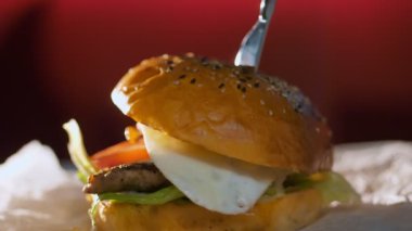 Hamburger. fast food. Yakın plan. Etli, sebzeli ve sahanda yumurtalı sulu burger. Döndürme. yemek yapmak