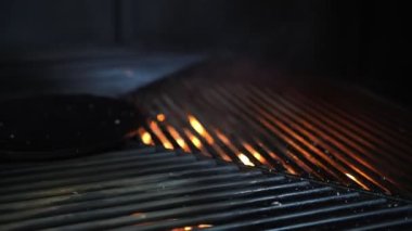Izgara yap. Alevli ızgara ızgara. Restoran mutfağında büyük ızgara çeviriyor. Izgaranın altından yanan bir ateş görülebilir. Barbekü.