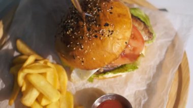 Hamburger. Yemek pişirmek. fast food. Yakın plan. Patates kızartmalı burger. Etli, sebzeli ve sahanda yumurtalı sulu burger. Patates kızartması ve domates sosuyla servis edilen hamburger. döndür.