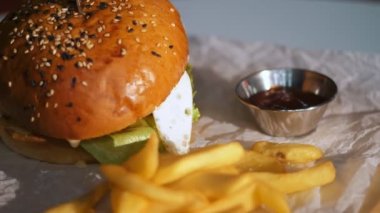 Hamburger. Yemek pişirmek. fast food. Yakın plan. Patates kızartmalı burger. Etli, sebzeli ve sahanda yumurtalı sulu burger. Patates kızartması ve domates sosuyla servis edilen hamburger. döndür.