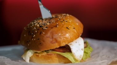 Hamburger. fast food. Yakın plan. Etli, sebzeli ve sahanda yumurtalı sulu burger. Döndürme. yemek yapmak