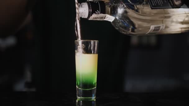 カクテルショット 接近中だ バーテンダーは異なるアルコール飲料を層に流し込みナイトクラブのバーカウンターにあるショットグラスに — ストック動画