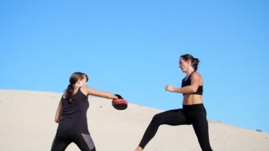 Siyah fitness takım elbiseli iki atletik, genç kadın bir çift içinde nişanlandık, başladı işe, ıssız plajda, mavi gökyüzü karşı yaz, sıcak güneşin altında dövüşmek tren. Ağır çekim.