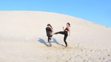 Siyah fitness takım elbiseli iki atletik, genç kadın bir çift içinde nişanlandık, başladı işe, tren, ağız kavgası ve tekme-up, ıssız sahilde yaz, sıcak güneşin altında gerçekleştirmek