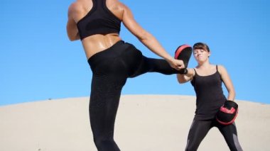 Siyah fitness takım elbiseli iki atletik, genç kadın bir çift içinde nişanlandık, başladı işe, ıssız plajda, mavi gökyüzü karşı yaz, sıcak güneşin altında dövüşmek tren. Ağır çekim.