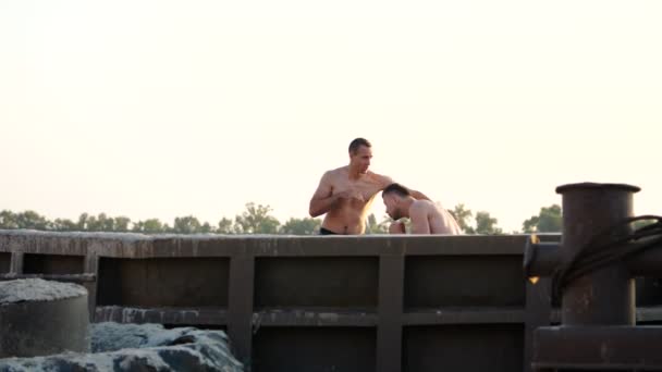 体育男青年赤裸裸的躯干 实践技术的罢工 在沙滩上 在货物港口 附近大型货物起重机 在夏天时 — 图库视频影像