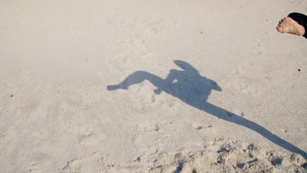 在沙滩上 你可以看到影子 一个执行抬腿动作的女运动员的轮廓 完成了踢腿动作 用影子进行了战斗 慢动作 — 图库视频影像