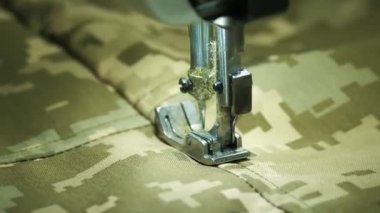 sewing. close-up. Fast movement of the sewing machine needle stitches camouflage military fabric. Sewing workshop.