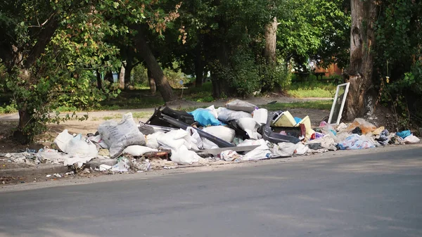 on ground, on side of road, lots of garbage is lying. scattered trash, rubbish, old things, car tires, broken glass, plastic. garbage dump. ecology, pollution of the environment. High quality photo