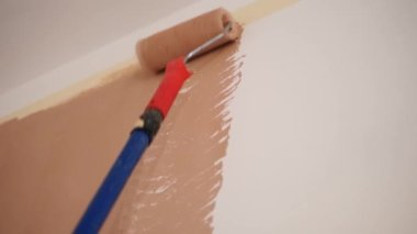 Duvar resmi. Su bazlı boya. Paten boyama. Onarım. Yakın plan. Boya silindiri kullanarak beyaz duvarı pembeye boyamak. Dairede, odada, evde, dairede tadilat yapıyor. Tamamlama ve inşaat işi