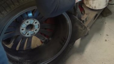 Lastik takılıyor. Tekerleği sökmek için hidrolik ya da mekanik baskı kullanan bir tamirci. Tamirci, profesyonel ekipman kullanarak lastiği jantından çıkarıyor.