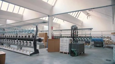 Tekstil fabrikası. İplik yapma süreci. İplik üretimi. Dönen yapım. Tekstil fabrikası ekipmanı. Fabrika makineleri makaraları ya da pamuklu ya da yün ipliklerle bobinleri geri sarıyor. 