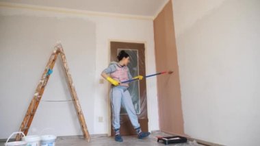 Duvar resmi. Su bazlı boya. Paten boyama. Onarım. Yakın plan. Boya silindiri kullanarak beyaz duvarı pembeye boyamak. Dairede, odada, evde, dairede tadilat yapıyor. Tamamlama ve inşaat işi