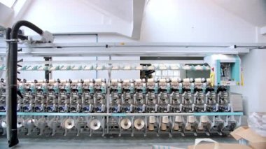 Tekstil fabrikası. İplik yapma süreci. İplik üretimi. Dönen yapım. Tekstil fabrikası ekipmanı. Fabrika makineleri makaraları ya da pamuklu ya da yün ipliklerle bobinleri geri sarıyor. 