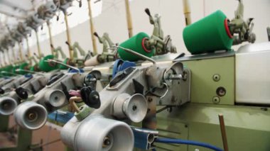 İplik üretimi. İplik yapma süreci. Dönen yapım. Tekstil fabrikası ekipmanı. Tekstil fabrikası. Fabrika makineleri makaraları ya da pamuklu ya da yün ipliklerle bobinleri geri sarıyor. 
