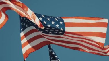 Mavi arka planda rüzgarda dalgalanan 2 Amerikan bayrağı. Amerikan Bayrağı. Mavi gökyüzünün önünde Amerika Birleşik Devletleri 'nin ünlü bayrağını sallıyordu. Yüksek kalite 4k görüntü