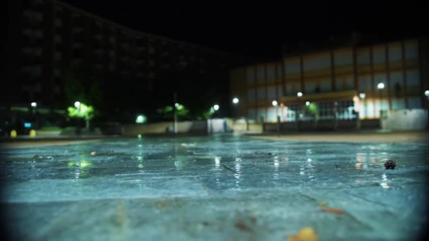 夜に雨が降る 光の雨 降雨量の閉鎖 プドルだ 水のプドル 水没した道路 街の歩道に光の反射と水たまり 夜の街 — ストック動画