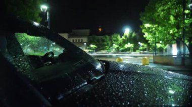 Yağmur. Yağmur damlaları içinde araba kaputu. Gece yağmur yağacak. Hafif yağmur. Yağmura yakın çekim. Su birikintisi Su birikintisi. Sualtı yolu. Şehir kaldırımında ışık yansıyan su birikintisi. İyi geceler. Geceleri şehir