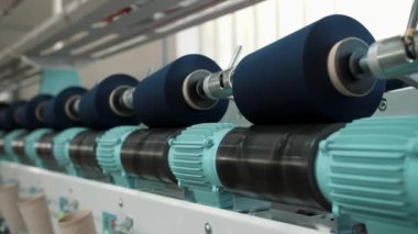İplik ipliklerinin yakın çekim makaraları. İplik üretimi. İplik yapma süreci. Dönen yapım. Tekstil fabrikası ekipmanı. Tekstil fabrikası. Fabrika makineleri makaraları ya da pamuklu bobinleri geri sarıyor