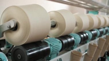 İplik ipliklerinin yakın çekim makaraları. İplik üretimi. Tekstil fabrikası. Dönen yapım. İplik yapma süreci. Tekstil fabrikası ekipmanı. Fabrika makineleri makaraları ya da pamuklu bobinleri geri sarıyor