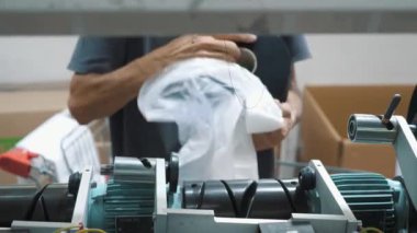 Bir işçi iplik makaraları taşır. Tekstil fabrikası ekipmanı. Tekstil fabrikası. Dönen yapım. İplik yapma süreci. İplik üretimi. Fabrika makineleri makaraları ya da pamuklu bobinleri geri sarıyor