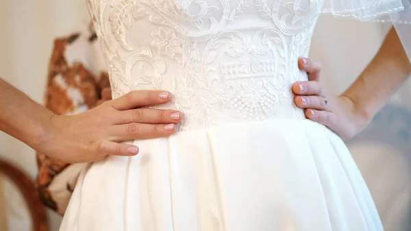 bride fees. the bride is dressed for the wedding. close-up of the bride\'s hands with a gentle manicure, against the background of a white lace dress . Wedding dress details, close up. High quality photo