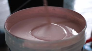 Resim yapmak. Onarım. Boyayı inşaat mikseriyle karıştırıyorum. Su bazlı boya. Su bazlı boyayı bir kovaya koyup çırpıcıyla karıştırmak. yakın plan.