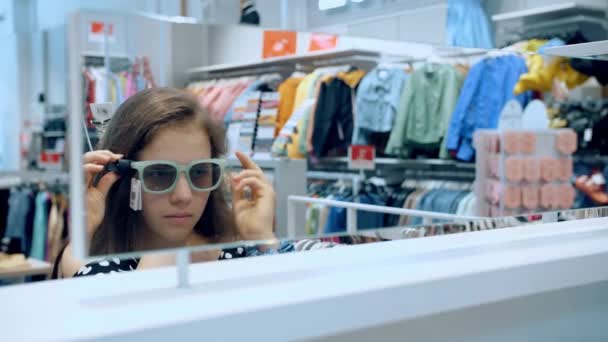 买太阳镜 少女试戴太阳镜 选择合适的太阳镜样式购买 在购物中心或超级市场销售太阳镜 — 图库视频影像
