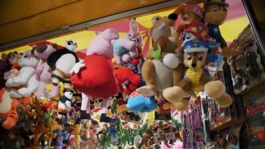 BIELLA, İtalya, 11 Haziran 2022: oyuncuları ayartmak için bir sürü sevimli oyuncakla dolu bir panayır tezgahı. Lunaparkın Gece Işıkları. Gece Eğlence Fuarı. Yanıp sönen ışık. Yüksek kalite 4k görüntü