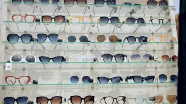 Güneş gözlüğü. Moda gözlüklerinin farklı modelleri olan bir vitrin. Gözlük. Alışveriş. Perakende mağazasından güneş gözlüğü almak. Optik dükkanı. 