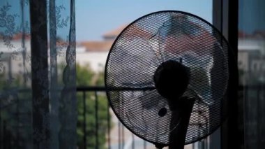  Havalandırma rüzgarı esiyor, sağa sola dönüyor. Yakın plan. Elektrikli vantilatör odayı soğutuyor. Elektrikli soğutma pervanesi yaz günü apartmanda çalışıyor.. 