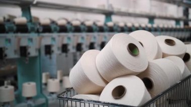 Bir sepetteki iplik maşaları. İplik üretimi. İplik yapma süreci. Dönen yapım. Tekstil fabrikası ekipmanı. Tekstil fabrikası. Fabrika makineleri makaraları ya da bobinleri geri sarıyor